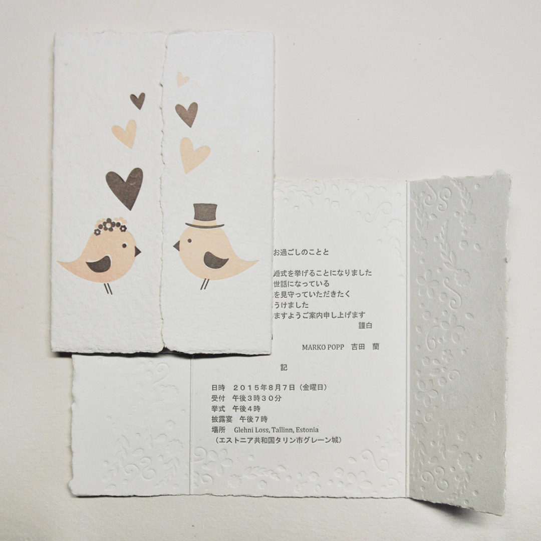 Letterpress printed wedding invitation with birds, hearts and flowers on handmade paper